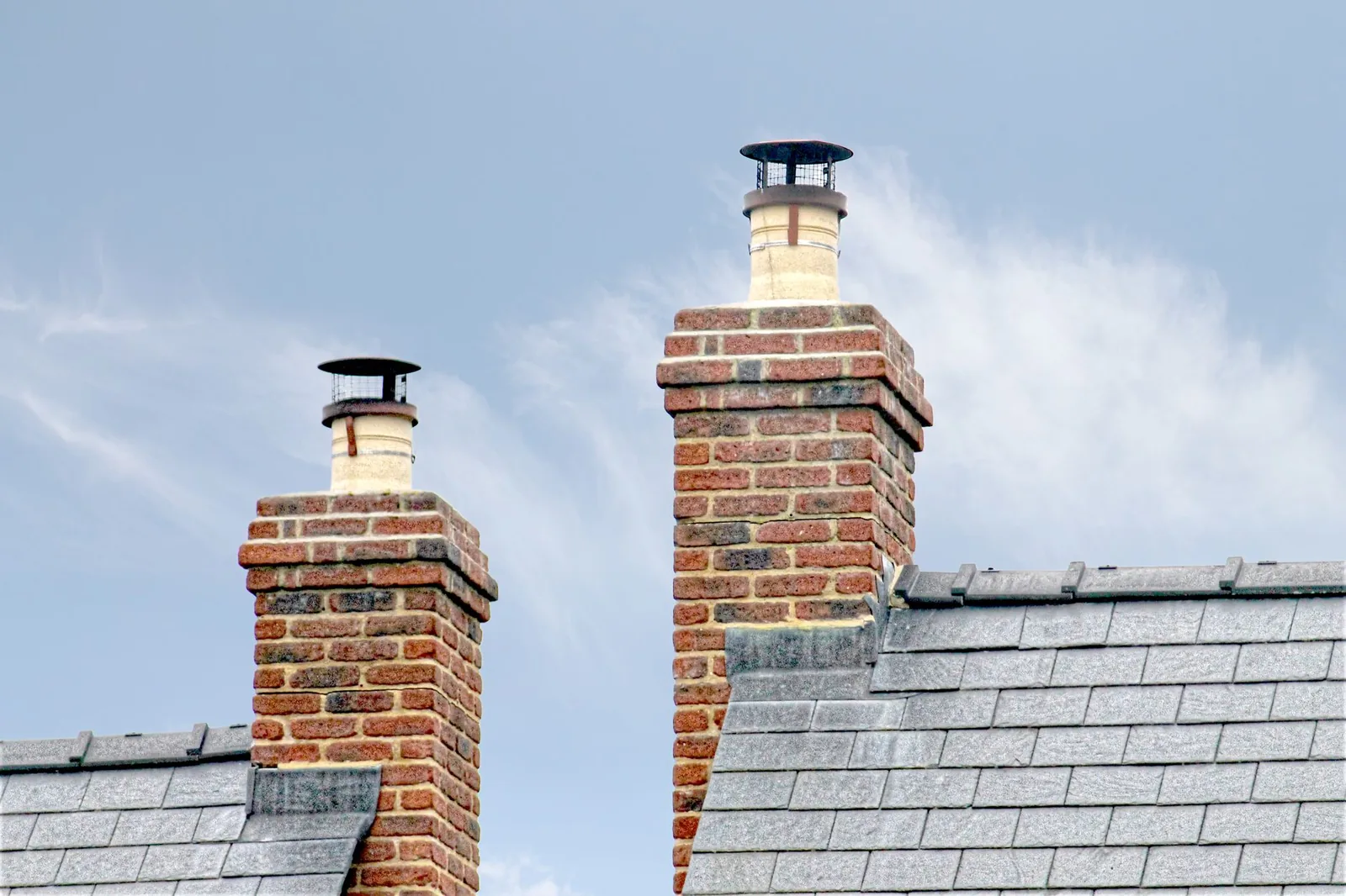 Brick chimneys with metal caps on a slate roof