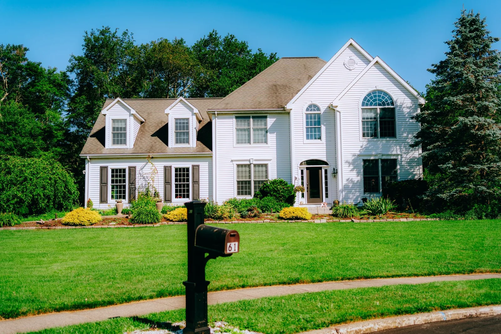 An elegant suburban house with a large, lush green lawn of the kind that suits a horizontal ground loop.