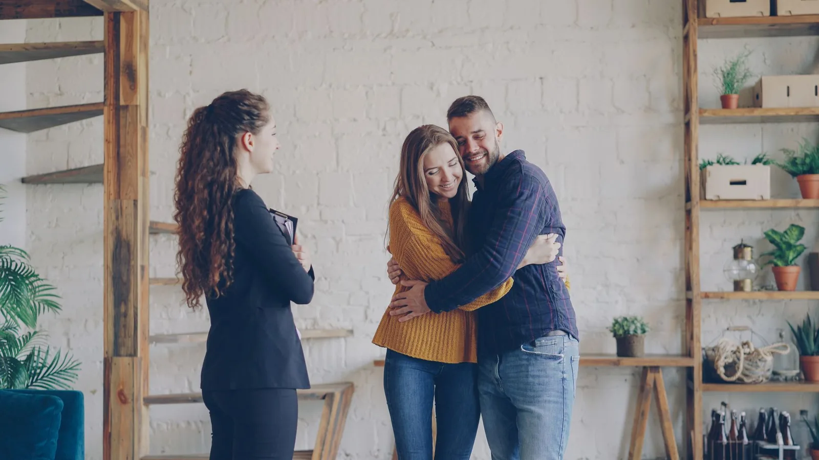 Realtor with a folder and a couple hugging