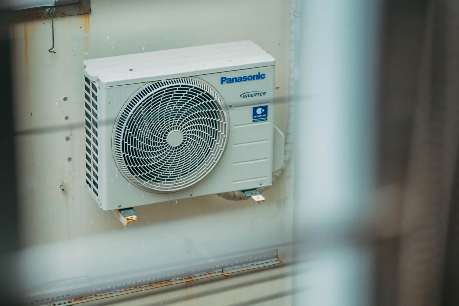An outdoor air conditioner unit mounted on a building wall on a clear day.