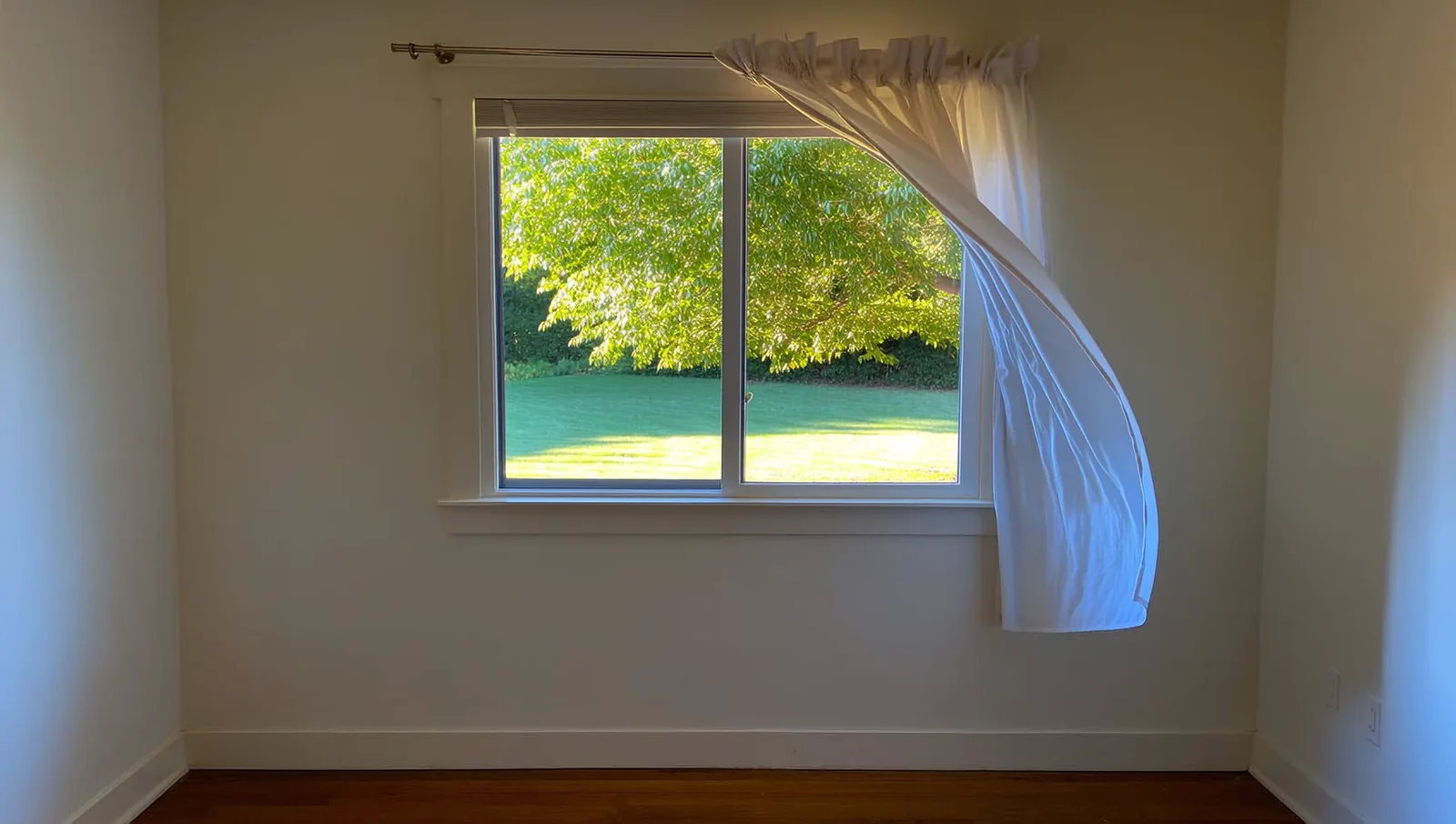 Open window with a white curtain blowing inward